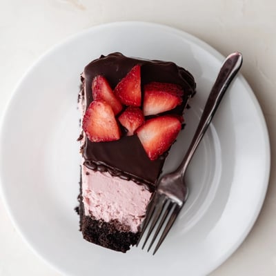 Fresh halved strawberries top a decadent Chocolate Covered Strawberry Cheesecake with a visible chocolate cookie crust layer and creamy filling.