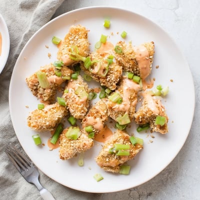 Spicy and tangy Quick Low Carb Bang Bang Chicken served hot on a platter garnished with fresh scallions and sesame seeds.